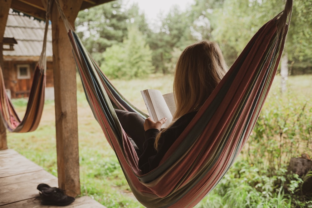 woman reading book on hammock