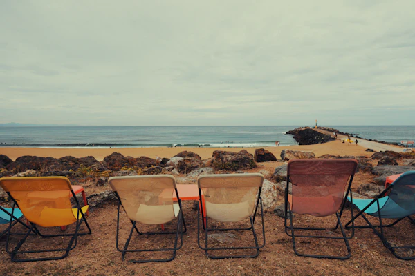 Empty folding chairs on a beach under a grey sky
