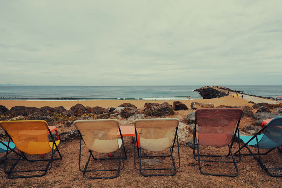 Empty folding chairs on a beach under a grey sky