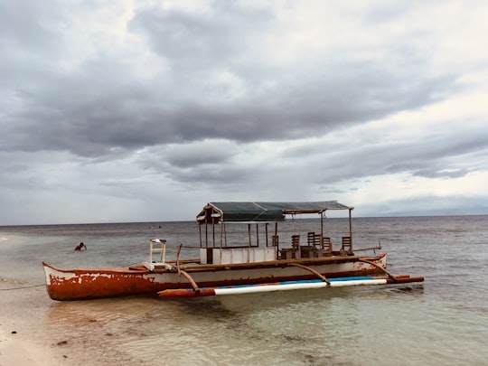 brown and white wooden dock on body of water under cloudy sky during daytime in Mantigue Island Philippines