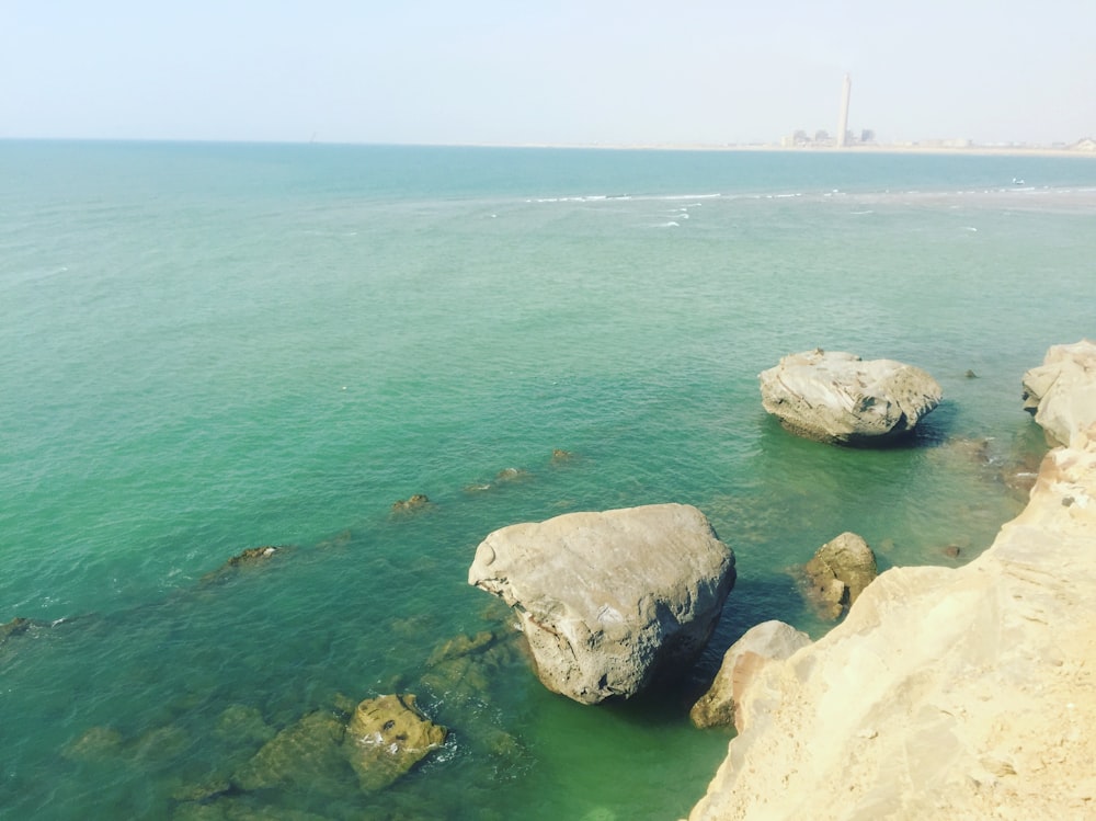 formação rochosa marrom no mar durante o dia