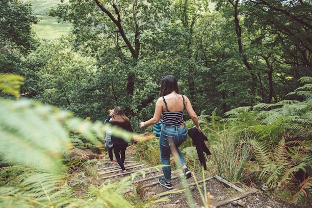 woman in blue denim shorts and black tank top walking on dirt road during daytime