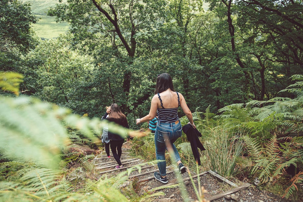 woman in blue denim shorts and black tank top walking on dirt road during daytime