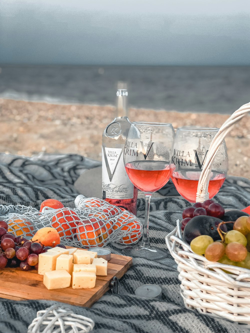 copa de vino transparente con vino tinto junto a canasta tejida marrón sobre tela blanca y negra