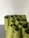 A collection of rolled-up green yoga mats are stacked against a plain white wall. The mats are tightly wound and arranged neatly on a gray floor, forming a cluster.