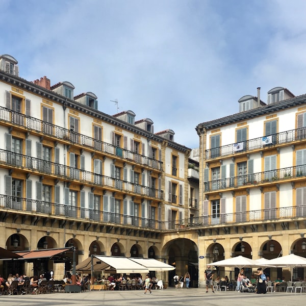 People walking past a grand beige stone building in San Sebastian