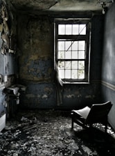 A dimly lit empty child's bedroom with peeling wallpaper and a lone toy on the floor.