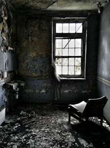 A dimly lit empty child's bedroom with peeling wallpaper and a lone toy on the floor.