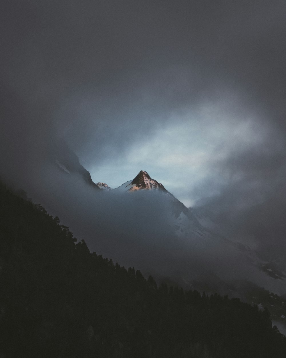 montanha coberta de neve sob céu nublado durante o dia