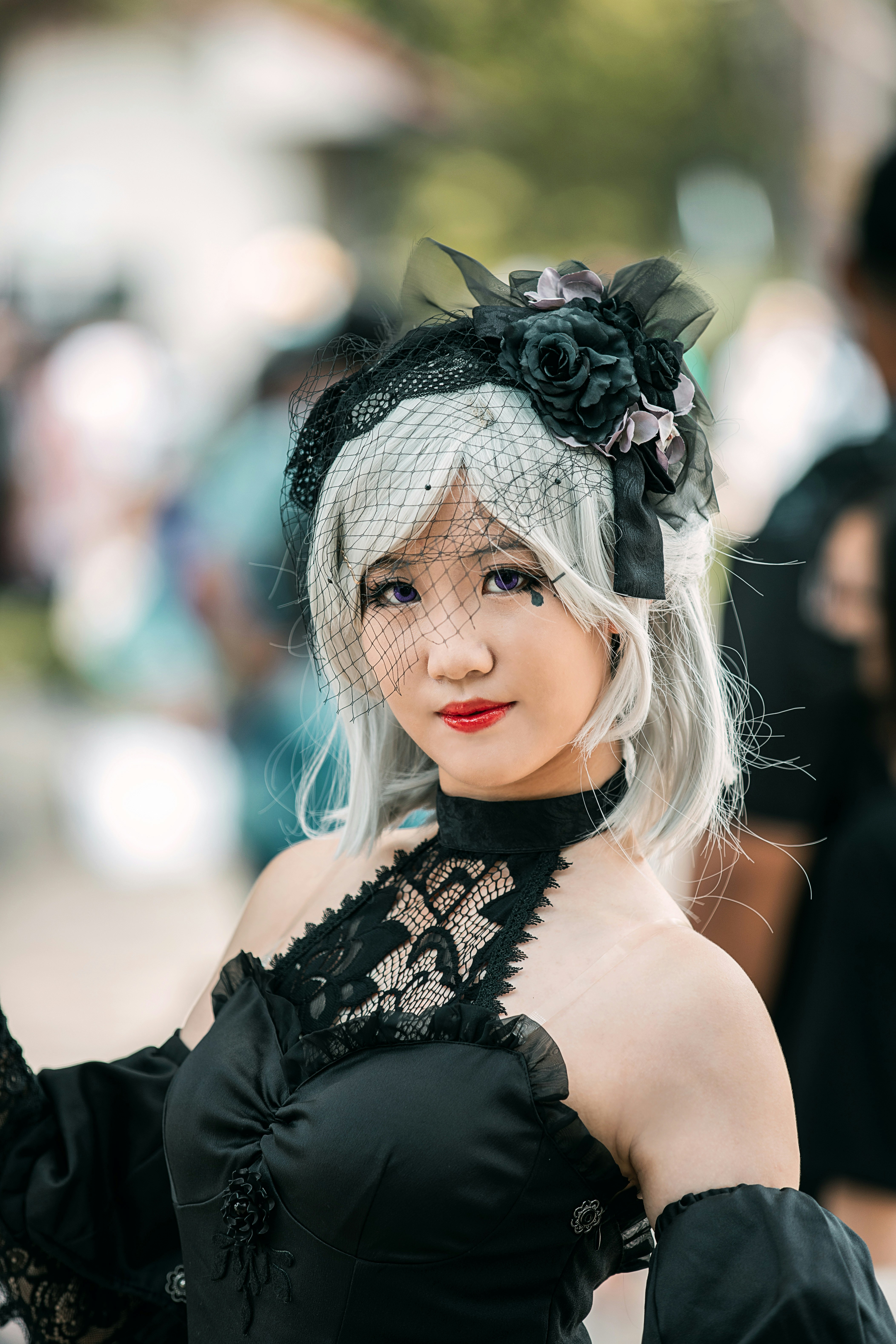 Wanita dengan atasan tanpa lengan hitam mengenakan hiasan kepala bunga hitam dan putih