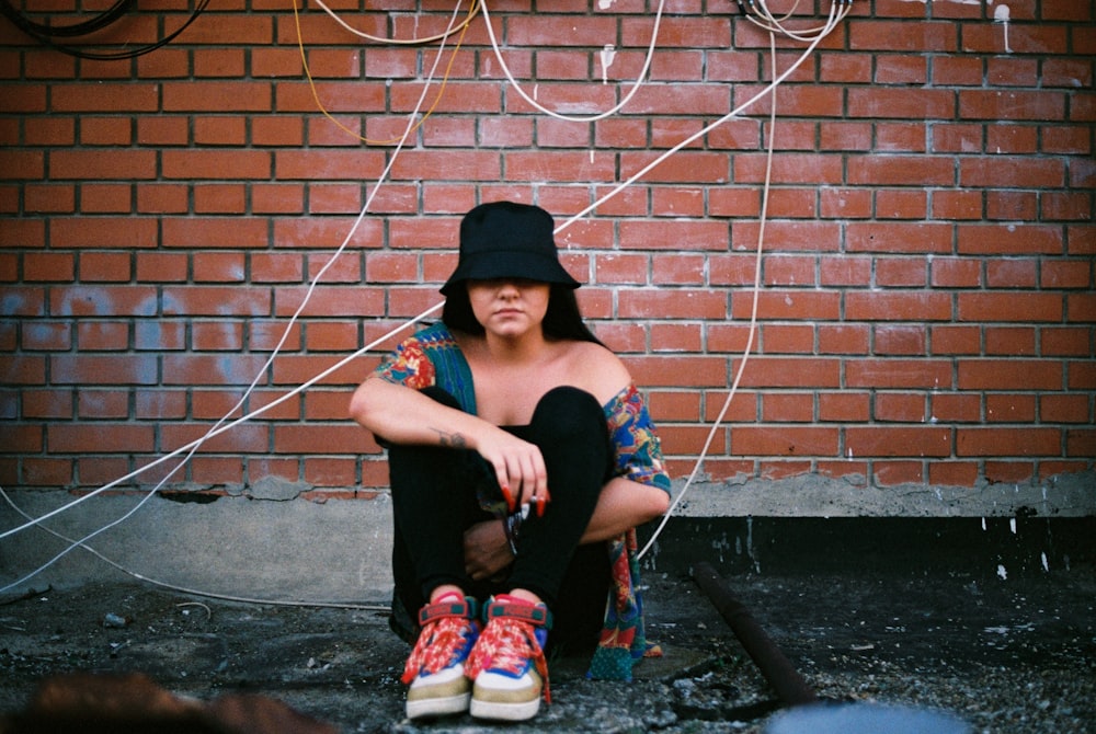 woman in black t-shirt and black pants sitting on concrete wall