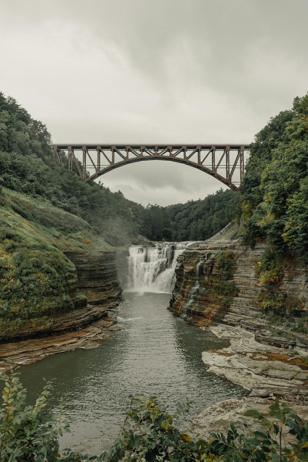 water falls under gray bridge