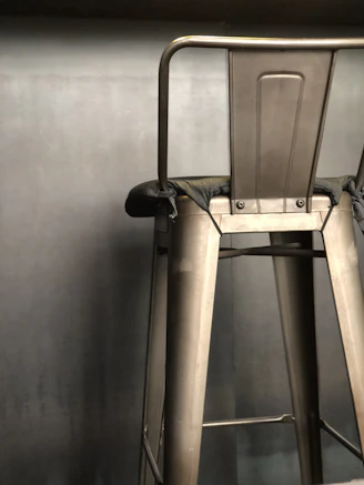 Close-up of a sleek industrial metal bar stool with a matte black finish in a cozy kitchen setting
