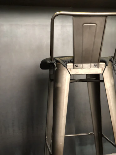 Close-up of a sleek industrial metal bar stool with a matte black finish in a cozy kitchen setting