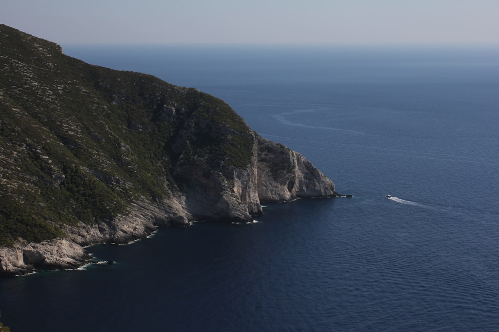 Barca bianca sul mare vicino alla montagna verde durante il giorno