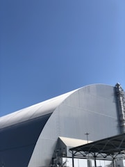 A large industrial steel warehouse under clear blue sky.