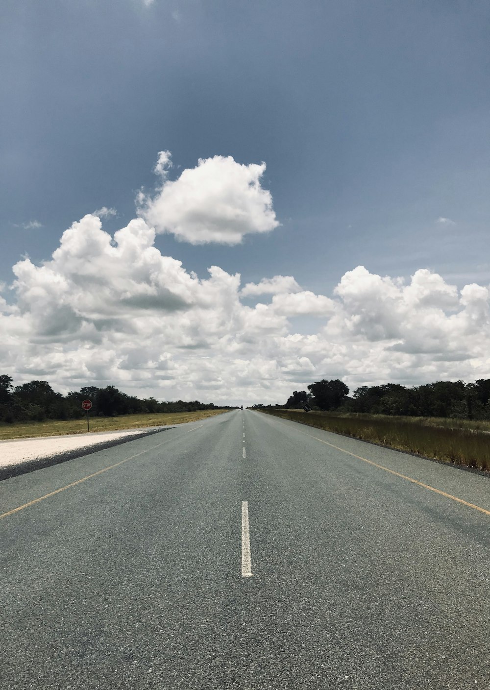 gray concrete road under white clouds and blue sky during daytime