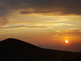 A serene sunset casting warm hues over a quiet countryside landscape.