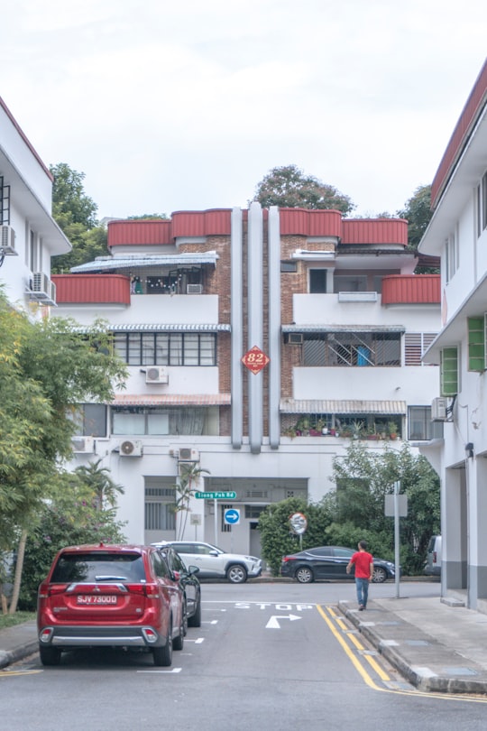 cars parked in front of white and red concrete building during daytime in Tiong Bahru Singapore