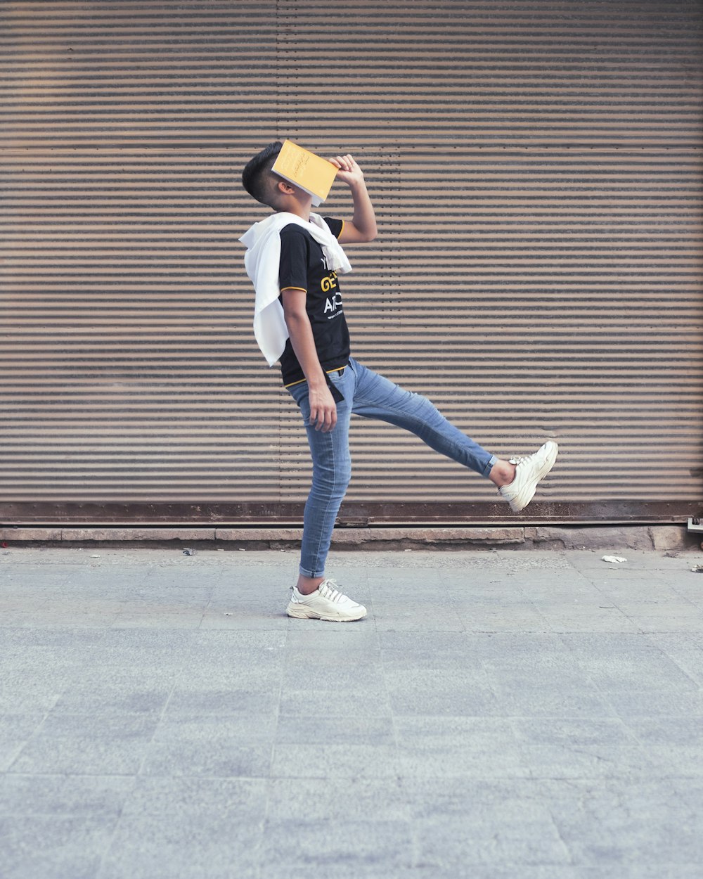 donna in camicia bianca e jeans blu in piedi sul marciapiede durante il giorno