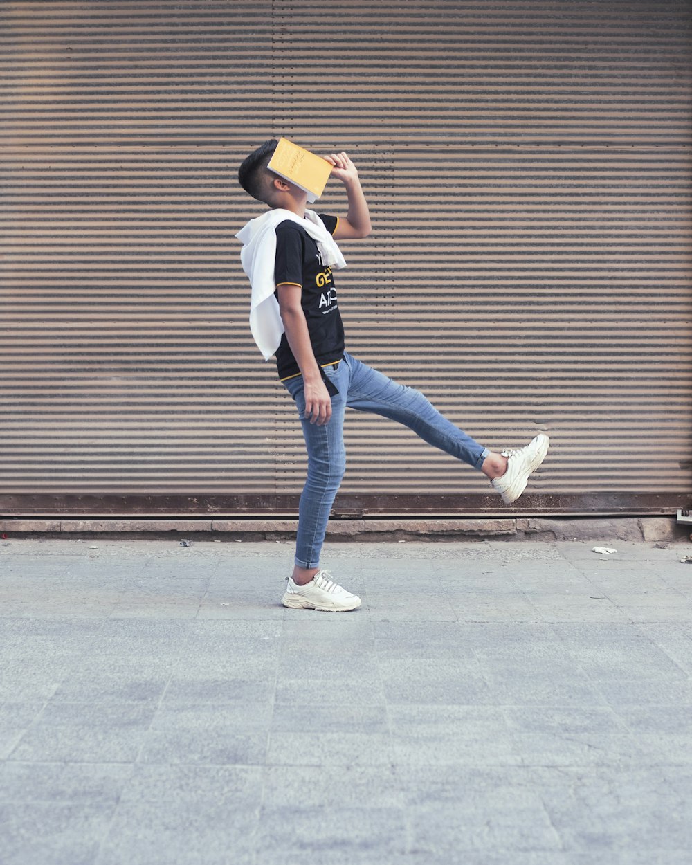 Femme en chemise blanche et jean bleu debout sur le trottoir pendant la journée