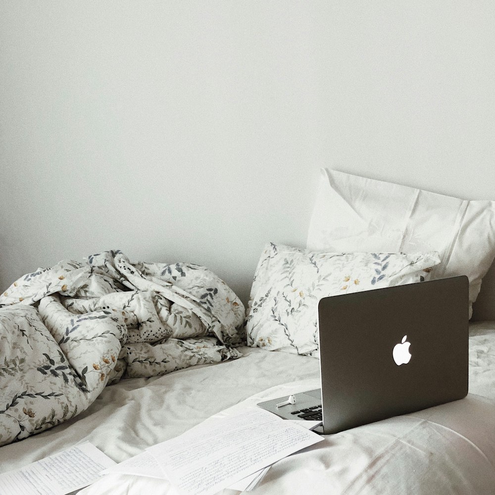 silver macbook on white bed