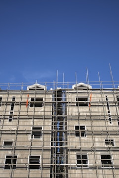 Workers installing steel frames on a multi-story commercial building under a clear blue sky.