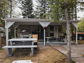 A stylish mobile cabin set up as a rental unit with a small porch and outdoor seating area.