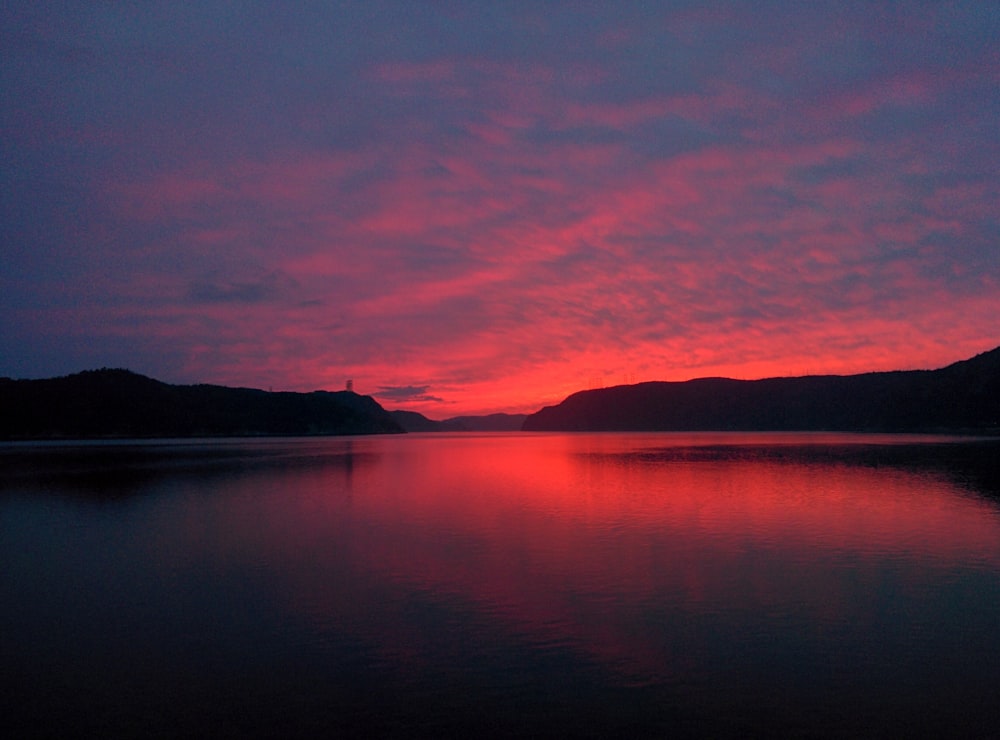 body of water near mountain during sunset