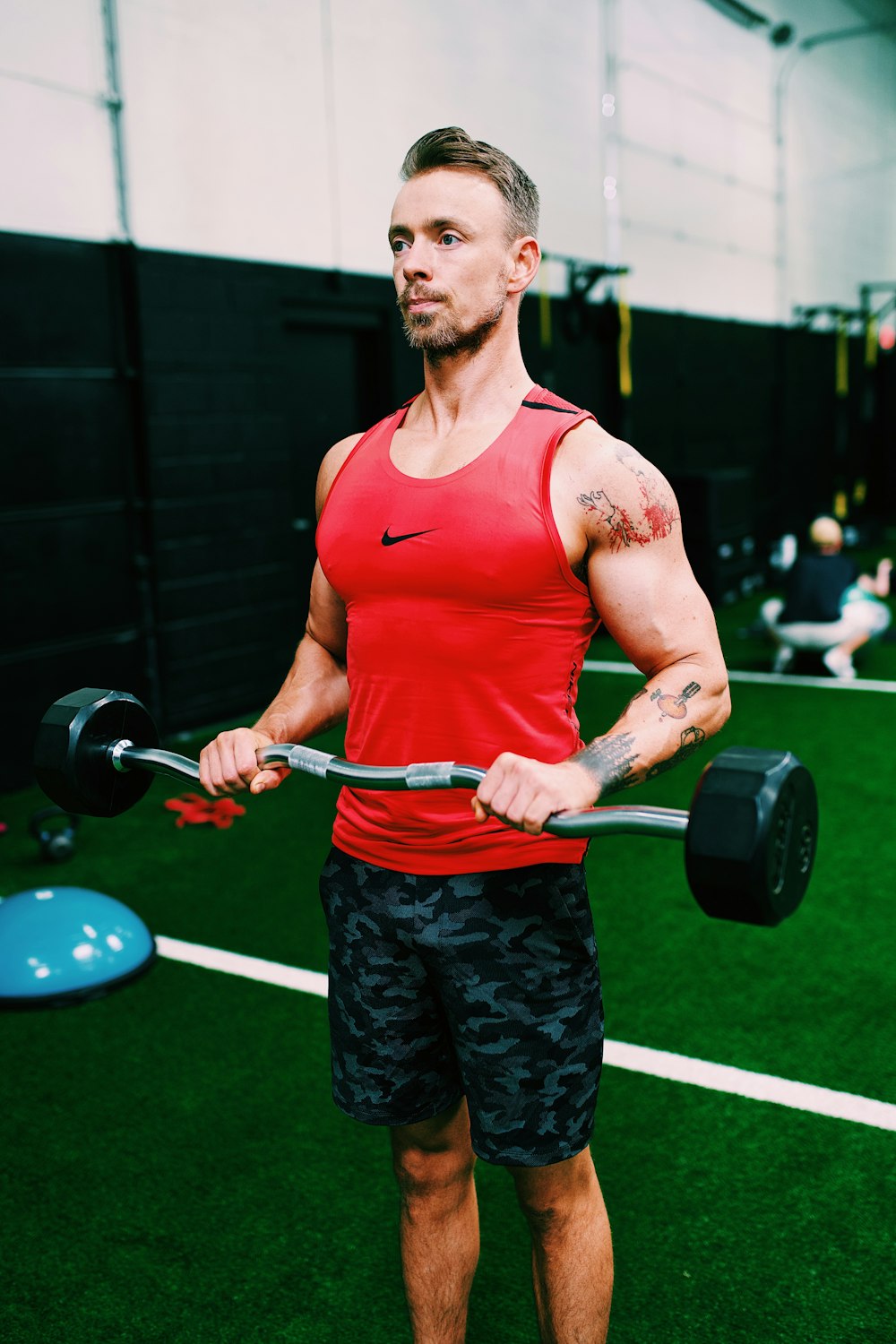 man in red tank top holding black dumbbell