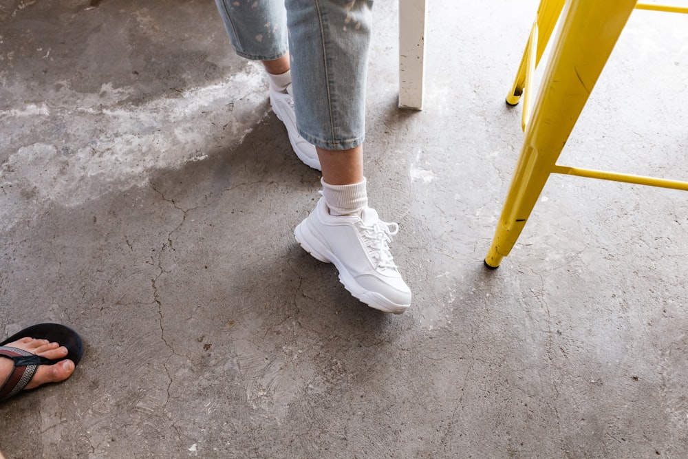 person in blue denim jeans and white sneakers