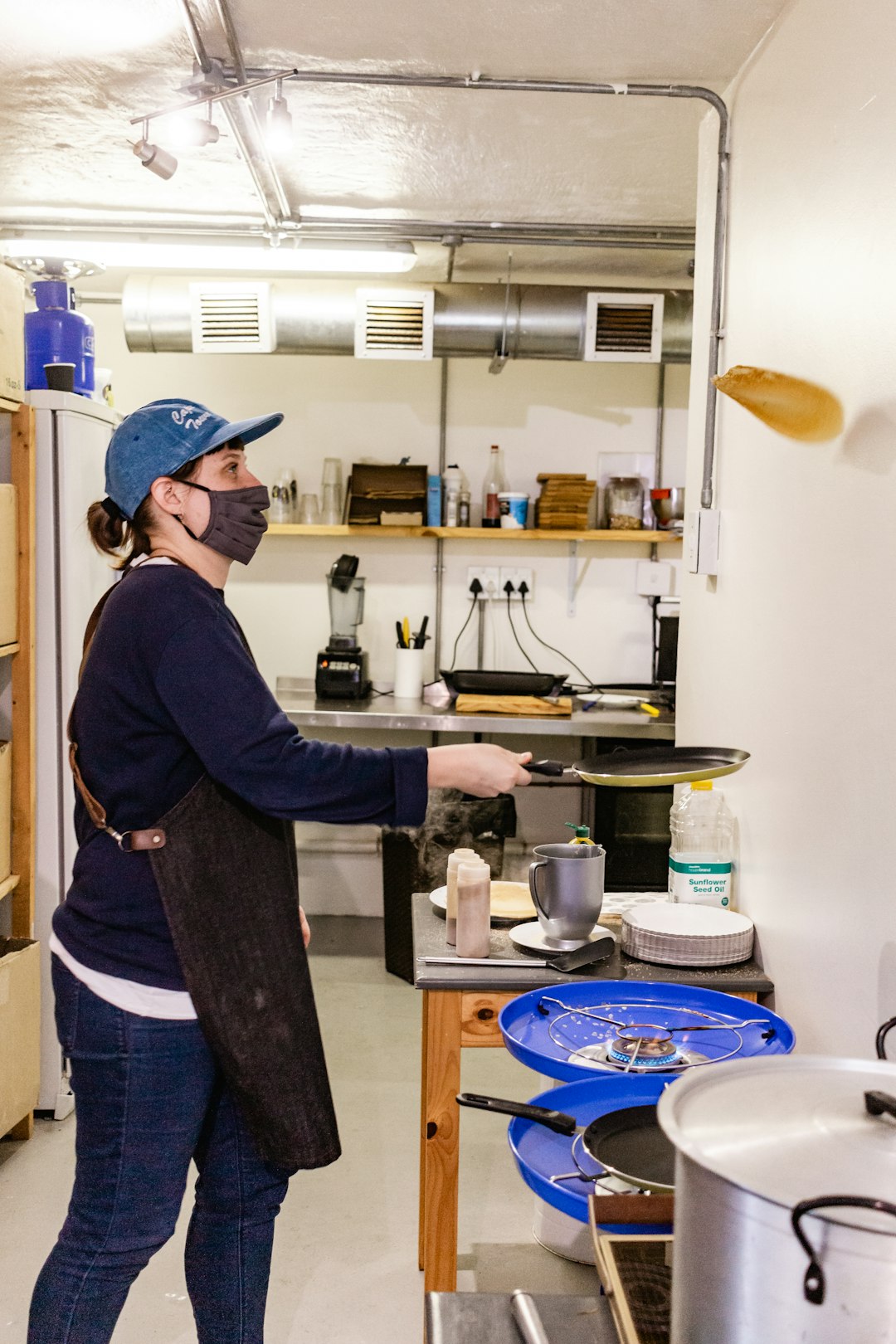 man in black long sleeve shirt and blue denim jeans standing near kitchen sink