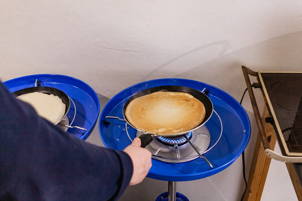 person in black long sleeve shirt holding blue plastic plate with brown liquid