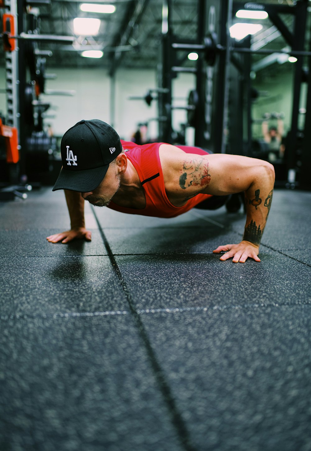 woman in red sports bra and black shorts doing push up on gray concrete road during