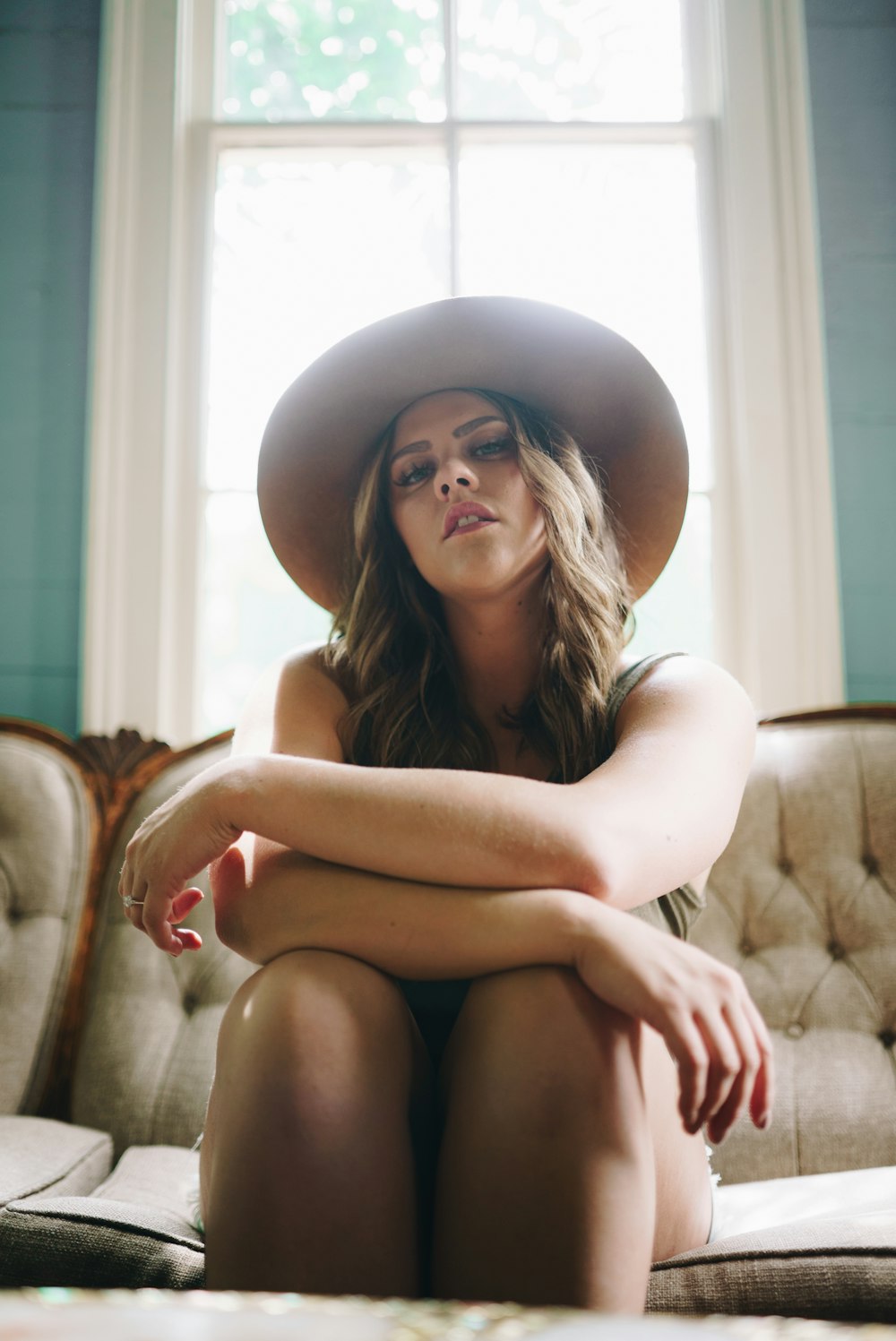 woman in white tank top and black shorts sitting on brown sofa chair