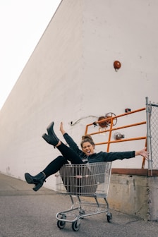 man in black jacket and black pants sitting on yellow metal fence