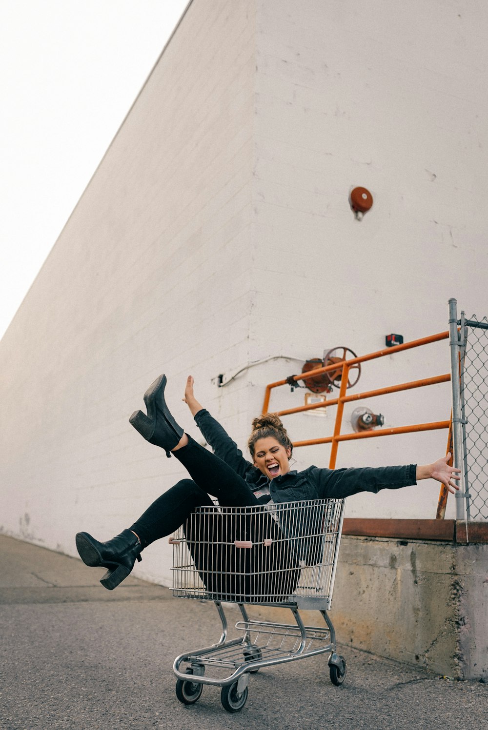 man in black jacket and black pants sitting on yellow metal fence