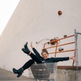 man in black jacket and black pants sitting on yellow metal fence