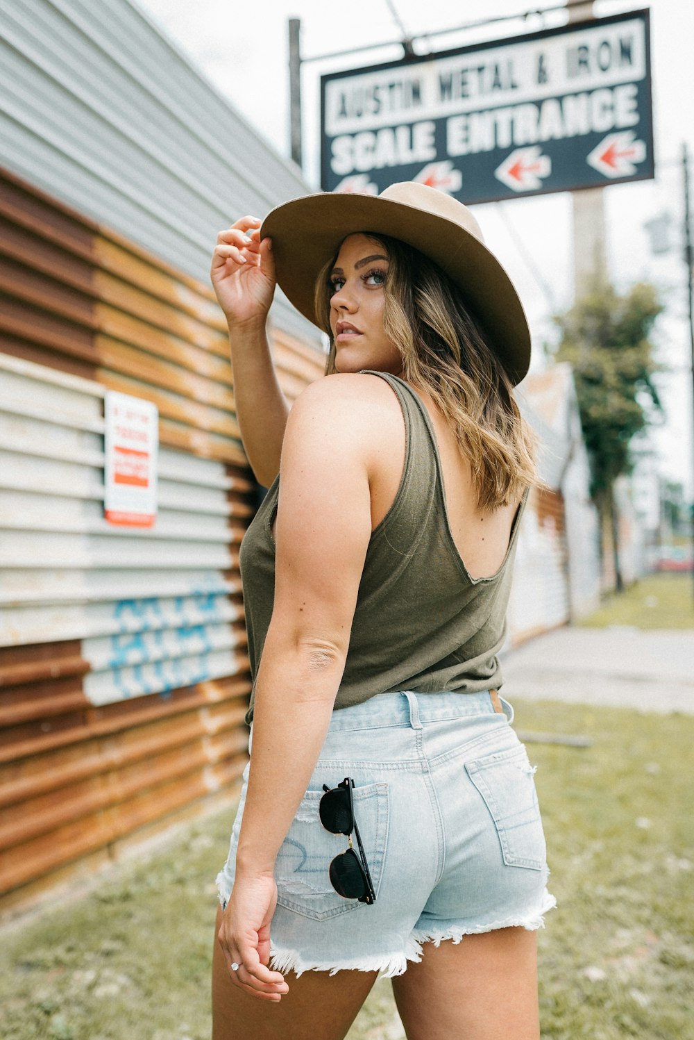 mulher na regata marrom e jeans azuis vestindo chapéu de cowboy marrom em pé perto de marrom