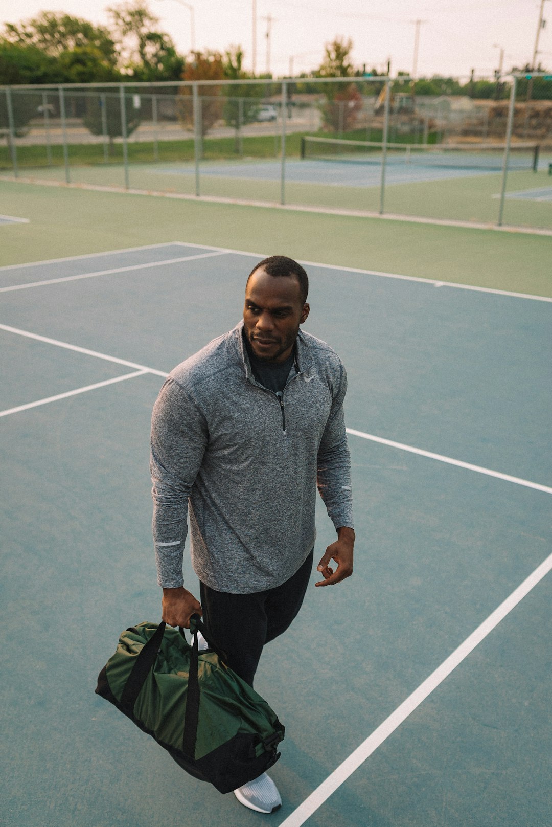 man in gray sweater and black pants holding black bag