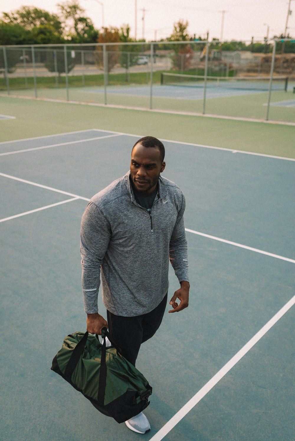 man in gray sweater and black pants holding black bag