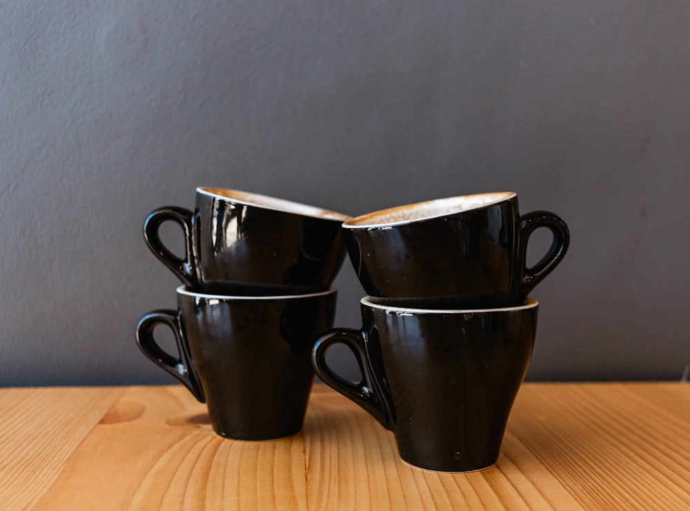 2 black ceramic mugs on brown wooden table