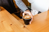 Smiling barista handing over a freshly brewed coffee to a happy customer.