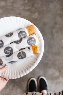 Smiling bakery owner holding a tray of pastries wrapped in soflux tissue paper with elegant branding.
