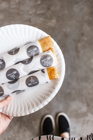 Smiling bakery owner holding a tray of pastries wrapped in soflux tissue paper with elegant branding.