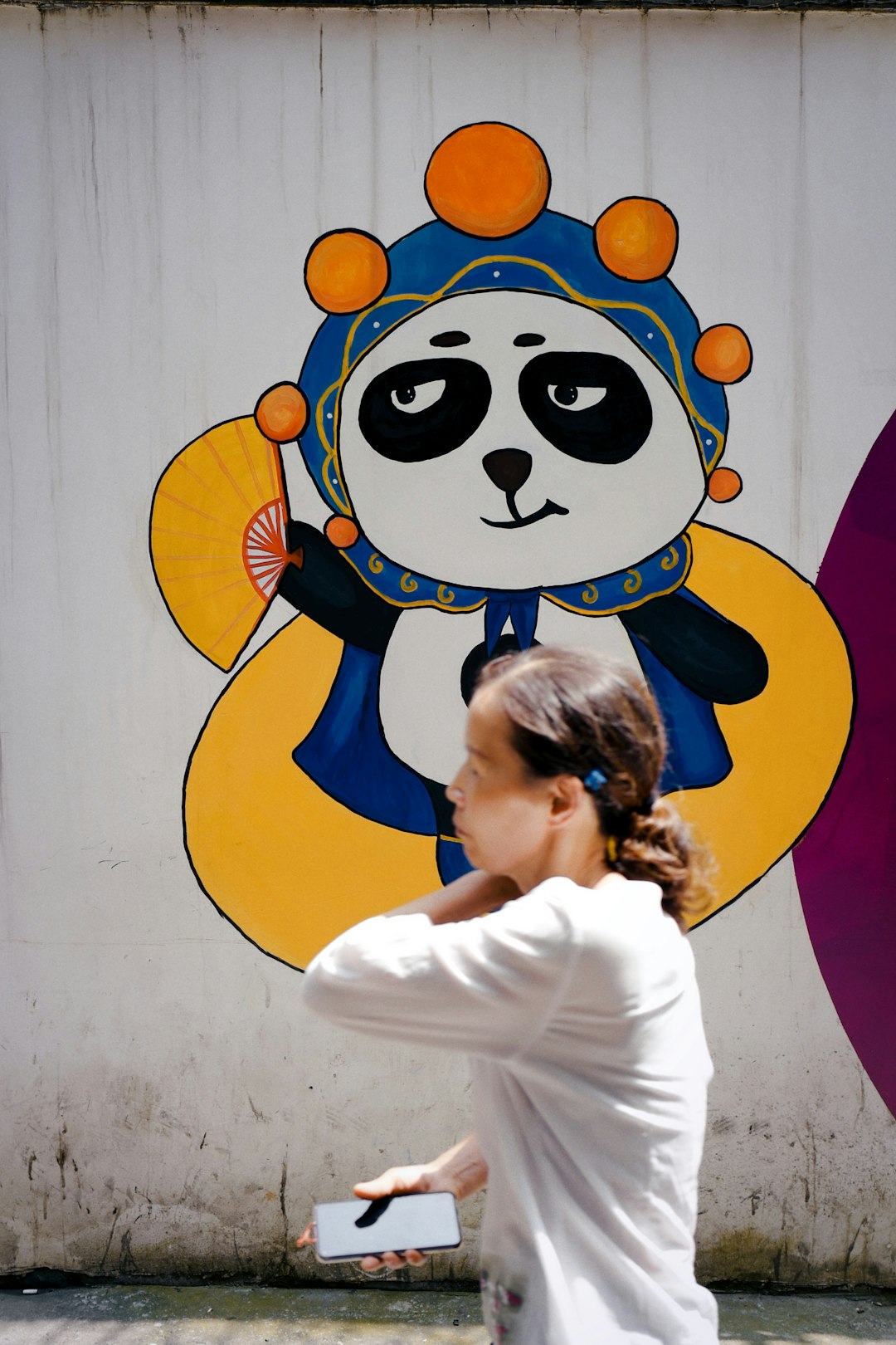 girl in white long sleeve shirt standing beside wall with blue and yellow m m m