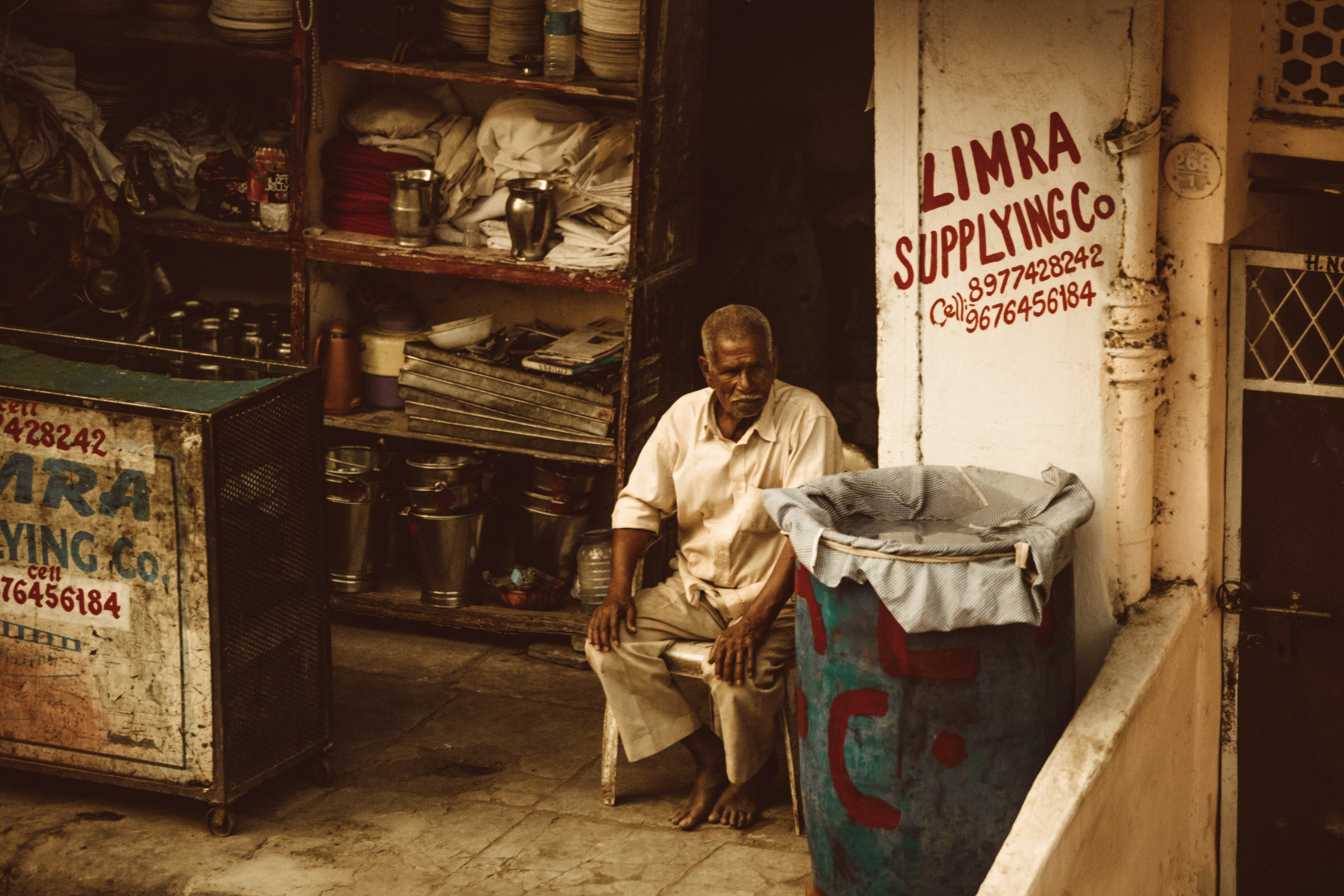 man in white thobe sitting on red plastic container