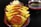 A serving dish contains several yellow chapatis folded over slices of spicy sausage, topped with garnish such as carrots and an onion flower. A small bowl of green chutney is placed beside the dish.