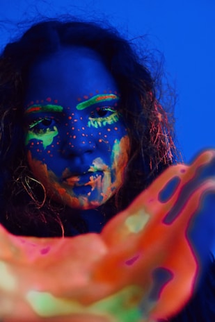 Close-up of festival-goers with painted faces illuminated by blue neon under a starry night.