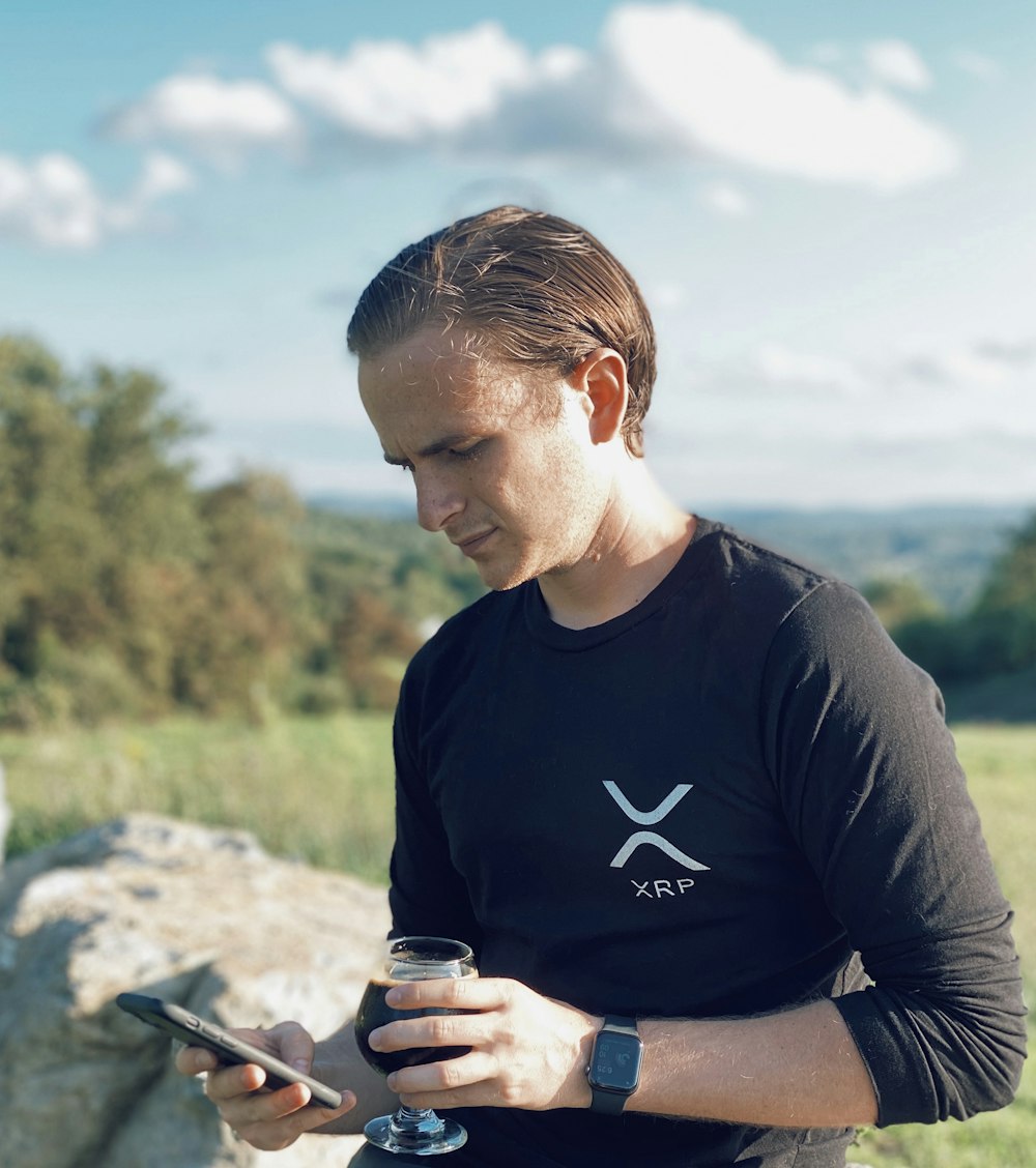 man in black crew neck t-shirt holding black smartphone